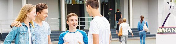 Eine Gruppe von glücklichen Jugendlichen unterhält sich im Eingangsbereich des Movie Park Germany vor einem Tag voller Abenteuer.